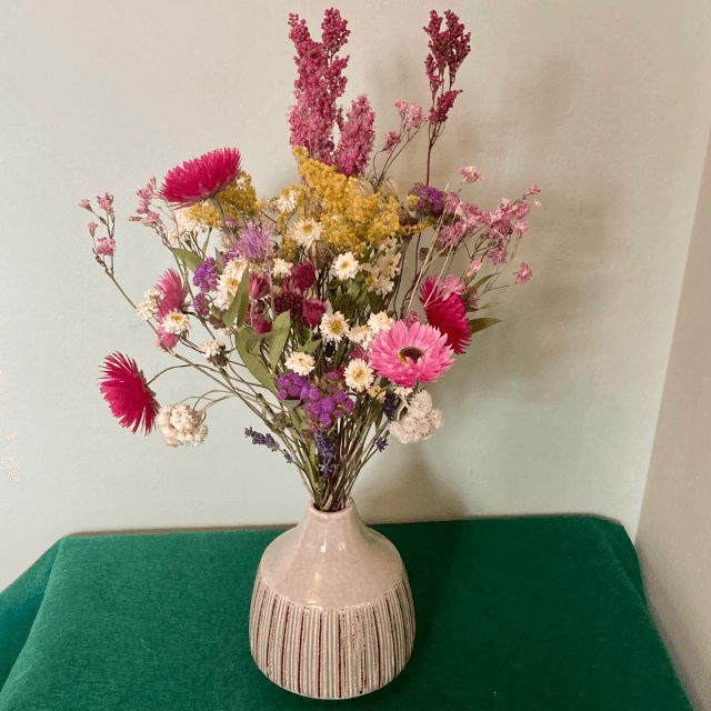 Local dried flower arrangement in vintage style green vase