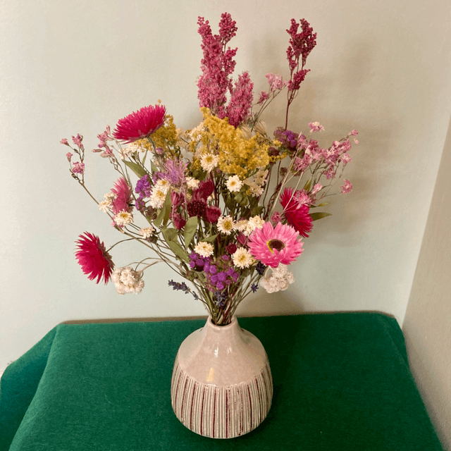 Local dried flower arrangement in vintage style green vase